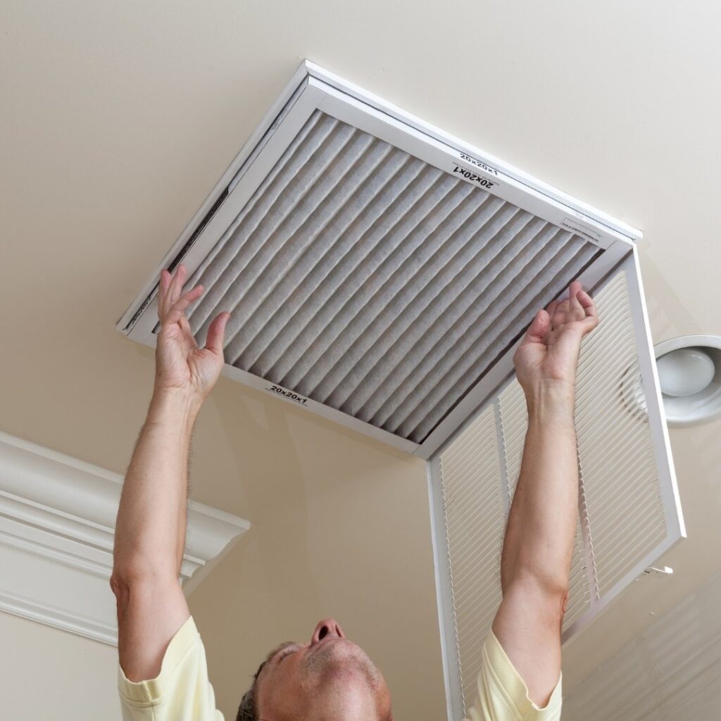 Senior Man Opening Air Conditioning Filter in Ceiling